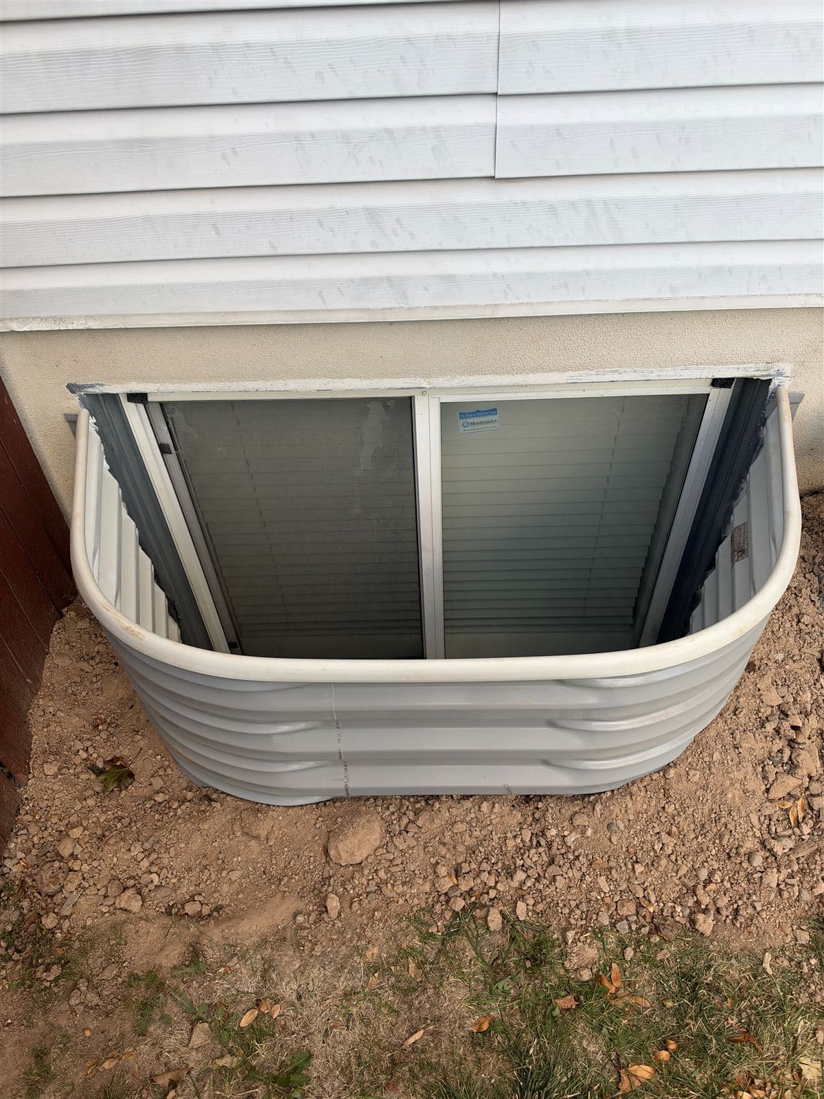 Newly installed window well against a home's foundation