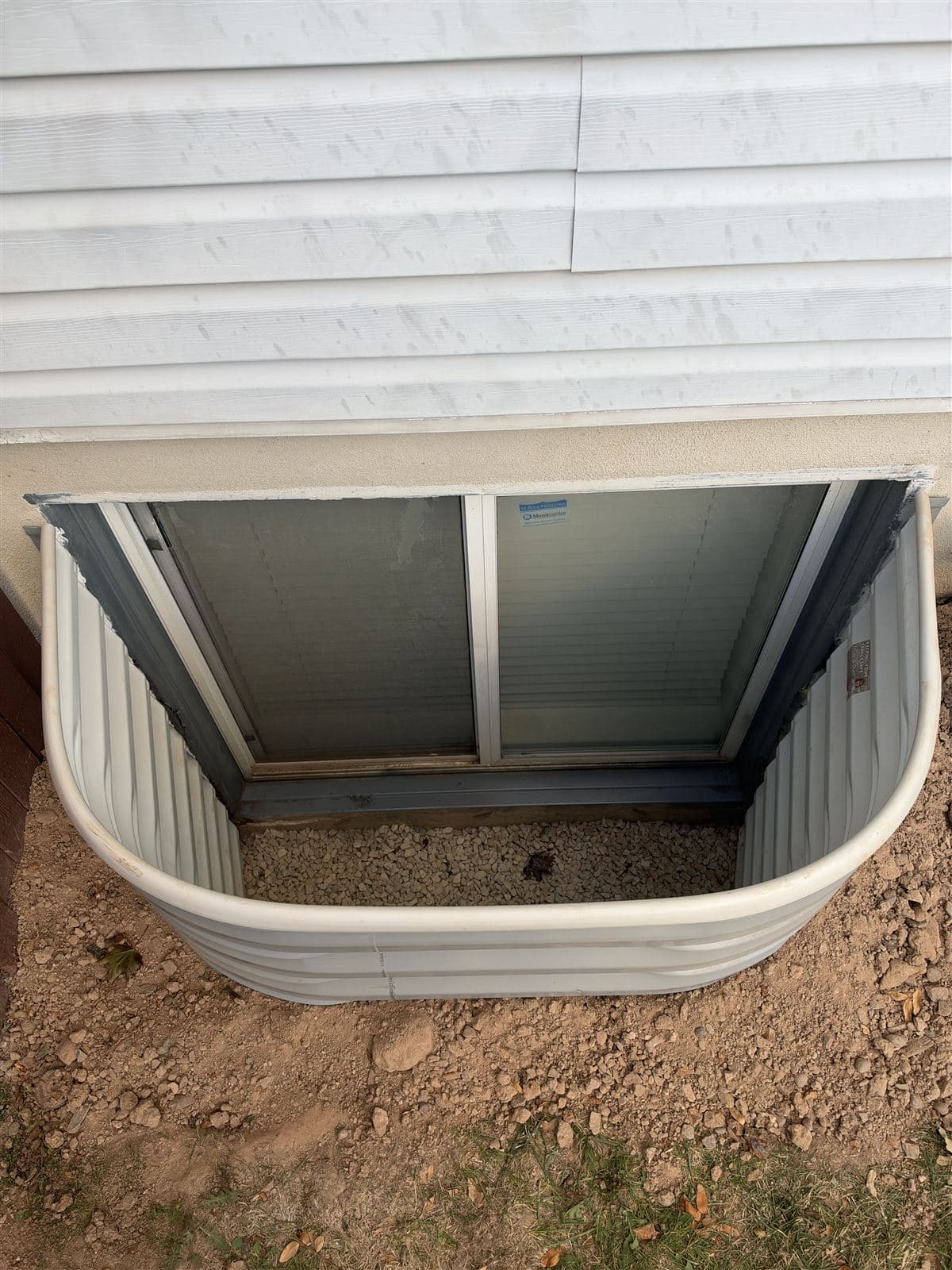 Finished window well with fresh drainage gravel in the bottom